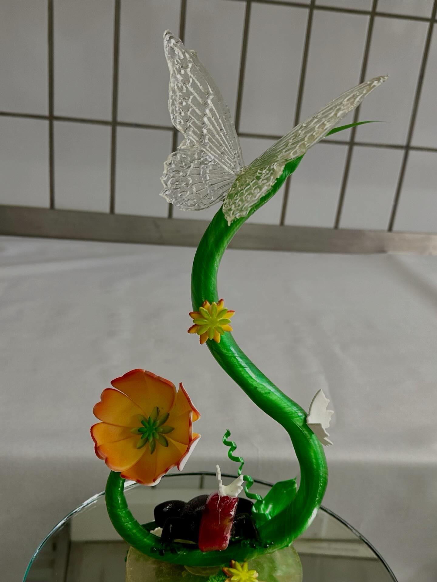 Pulled and blown sugar showpiece with a green stem, orange flower and glass butterfly